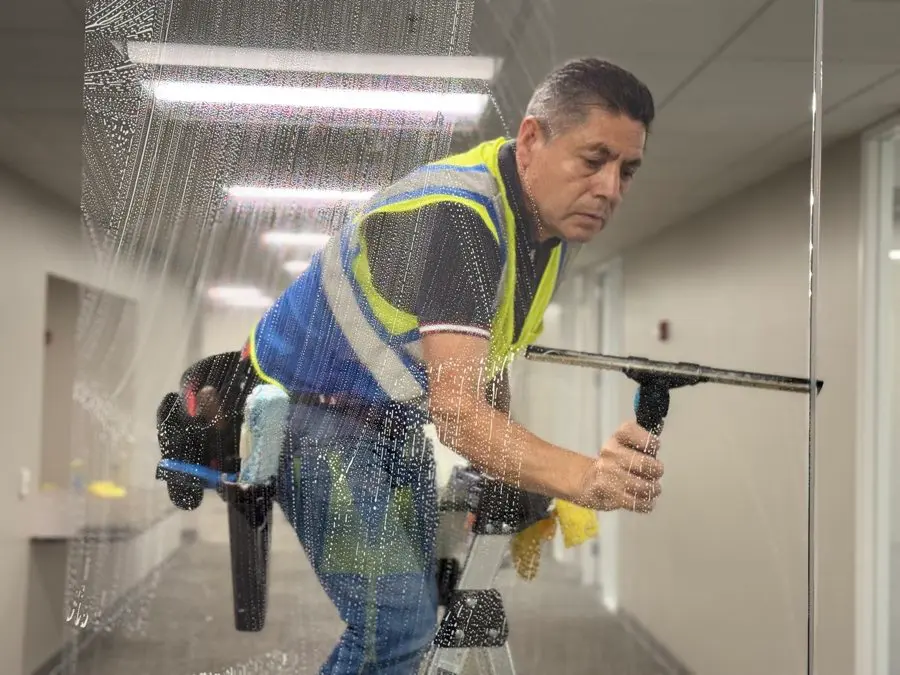 Omega crew member squeegeeing interior office glass
