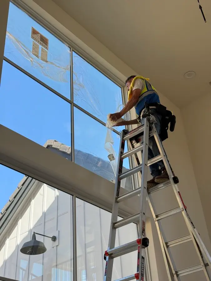 Omega crew member on a ladder detailing tall stairwell windows